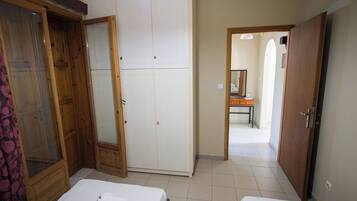 A bedroom with two beds, a wardrobe, and a bathroom visible through an open door.