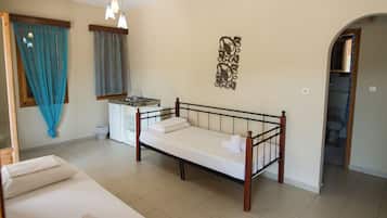 A bedroom with a bed, a small kitchenette, and a bathroom visible through an archway.