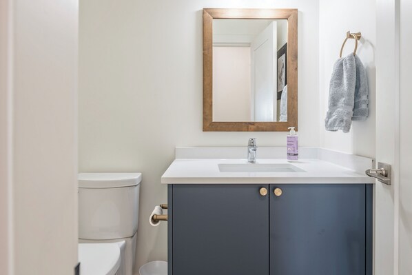 A bathroom with a white sink, a mirror with a wooden frame, a towel hanging on a towel ring, and a toilet.