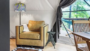 Una habitación con carpa, un sillón amarillo, una mesita y una lámpara de colores.