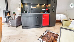 Una cocina compacta con estufa de leña, un refrigerador rojo y un comedor con mesa y sillas.