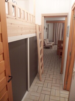 A narrow hallway with a wooden ladder leading to a room with a sliding door. A chair and a small table are visible in the background. - 3rd floor, swimming pool, balcony, tv, ski locker, 43m², Valloire (Valloire)
