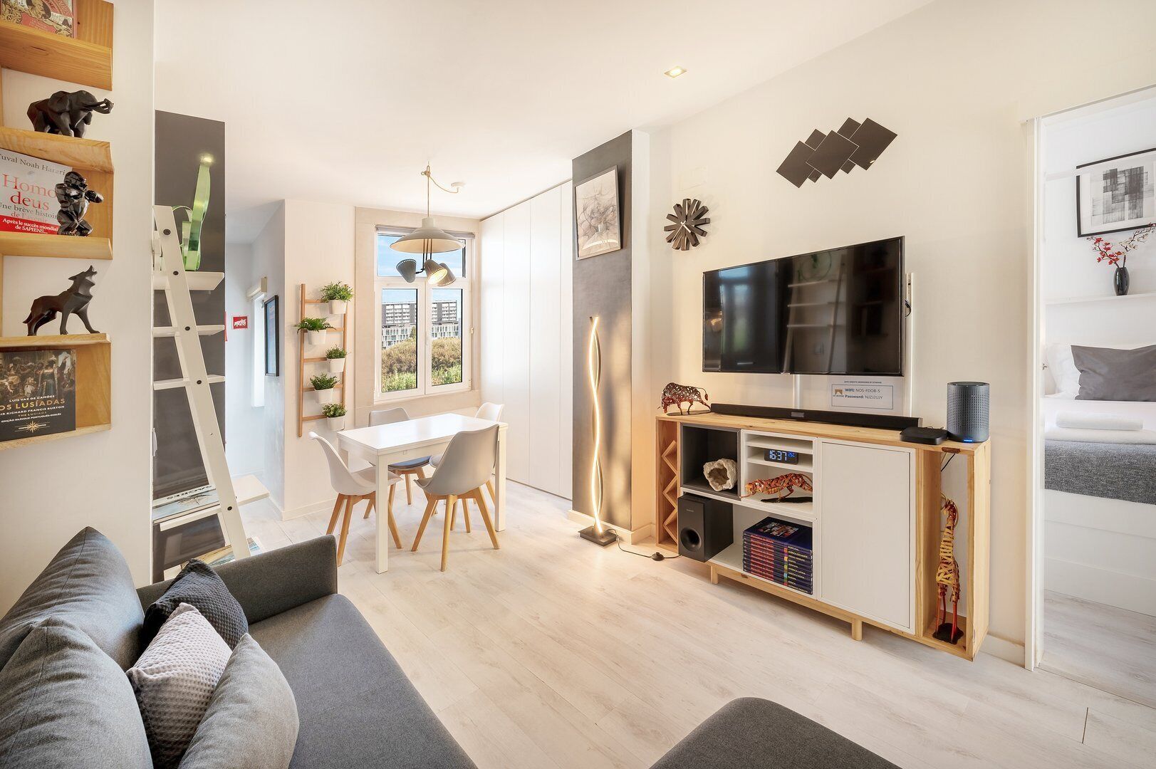 Ein modernes Wohnzimmer mit Fernseher, Sofa, Esstisch und Blick auf die Stadt.