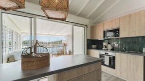 A modern kitchen with wooden cabinets, a large island, and a view of the marina. - Cosy, refurbished apartment, marina view (Le Gosier)