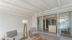 A modern, well-lit room with wooden furniture, a sofa, two chairs, a small table, and a floor lamp. - Cosy, refurbished apartment, marina view (Le Gosier)