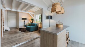 A spacious living area with a wooden floor, a blue sofa, a coffee table, and a hanging woven light fixture. - Cosy, refurbished apartment, marina view (Le Gosier)