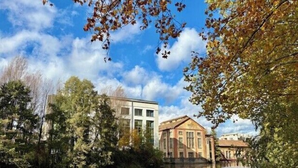 Uitzicht op een rivier met gebouwen, bomen en een heldere lucht.