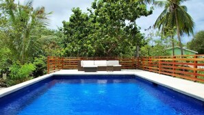 Ein rechteckiger Pool mit Holzterrasse und Sitzbereich.