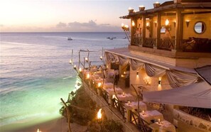An outdoor restaurant with tables and chairs overlooking the sea.