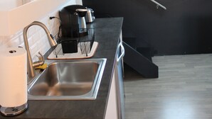 Une cuisine moderne avec un évier en acier inoxydable, une machine à café et un panneau « BIENVENUE » accroché au mur.