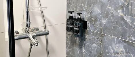 A shower with a handheld showerhead and a wall-mounted control panel.