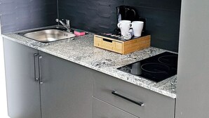 A kitchen with a microwave, sink, and a wooden countertop. - Hira Boarding Aparthotel (Dingolfing)