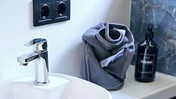A bathroom with a white sink, wooden cabinets, a towel, and a bottle of hand soap.
