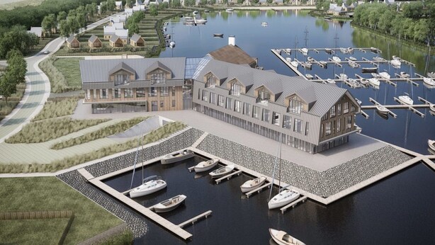An aerial view of a marina with boats docked, a large building with a modern design, and surrounding greenery. - Beautiful Apartment With Beautiful Views of the Lively Marina (Kamperland)