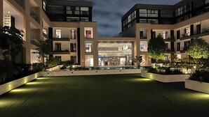 A modern building with multiple floors, large windows, and a central open space with seating. - Easy Stay at Embassy Gardens Apartment (Accra)