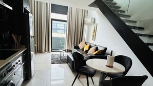 A modern living room with a dining area, a kitchen, and a staircase. - Easy Stay at Embassy Gardens Apartment (Accra)