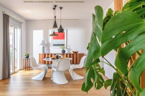 A modern dining area with a round table, white chairs, and pendant lighting. - Artful City Loft w. Rooftop Terrace · Near Beach (Chania)