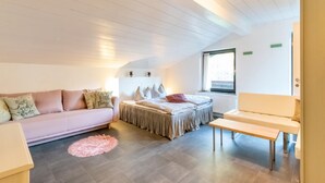 A room with a bed, a sofa, a small table, and a window.