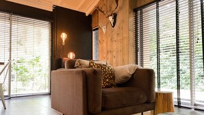 A cozy living room with a brown sofa, a round coffee table, and a rustic wall with a deer skull. - Lush Holiday Home in Rheezerveen With Hot Tub (Rheezerveen)