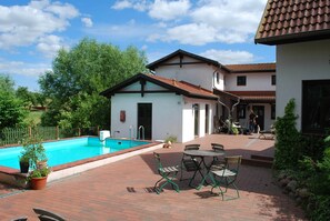 A swimming pool, outdoor seating, and a building with a tiled roof. - Comfortable Apartment in Quaint Holiday Village (Dargun)