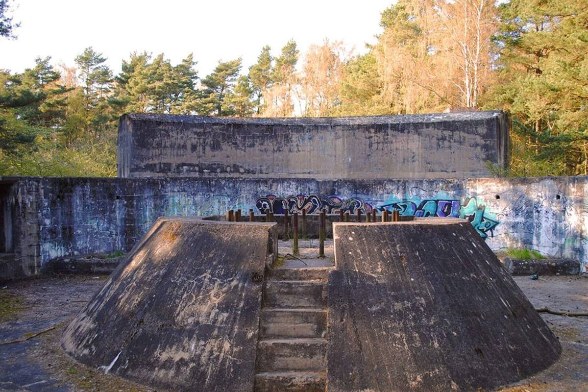 An abandoned building with graffiti on the walls and concrete ramps leading to a staircase.