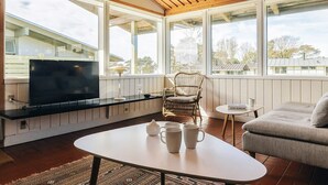 A cozy living room with a TV, a wicker chair, a round coffee table, and a sofa. - 6 Person Holiday Home on a Holiday Park in Gilleleje (Gilleleje)