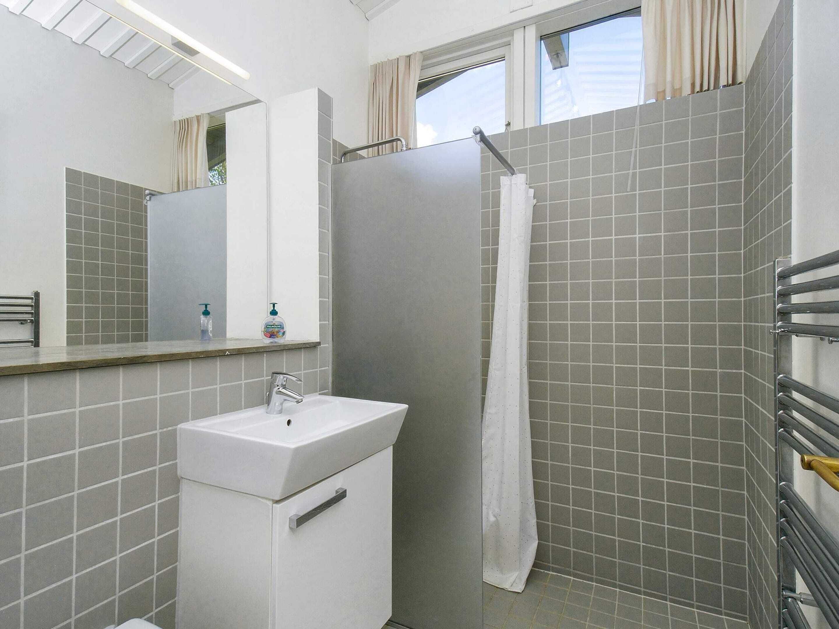 A bathroom with a white sink, mirror, and shower.