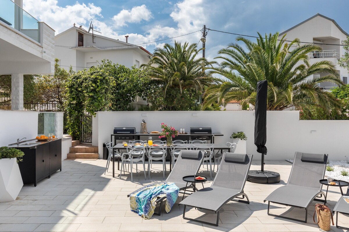 An outdoor patio with a grill, lounge chairs, and a dining area.