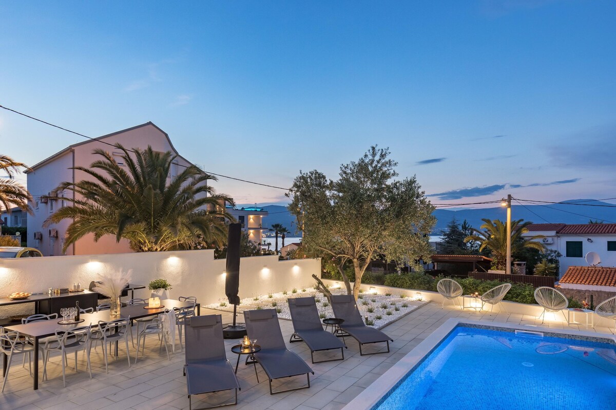 A poolside area with lounge chairs, a dining table, and a pool.