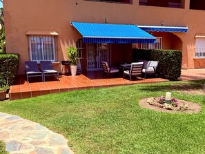 A patio area with outdoor seating, a covered area, and a well-maintained lawn. - Coastal Apartment/pool/garden/kingbed/acon/freep (Estepona)