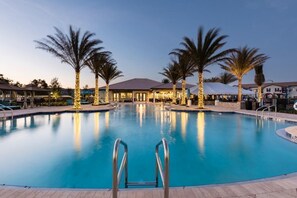 Ein Schwimmbad mit Palmen und einem Gebäude im Hintergrund.