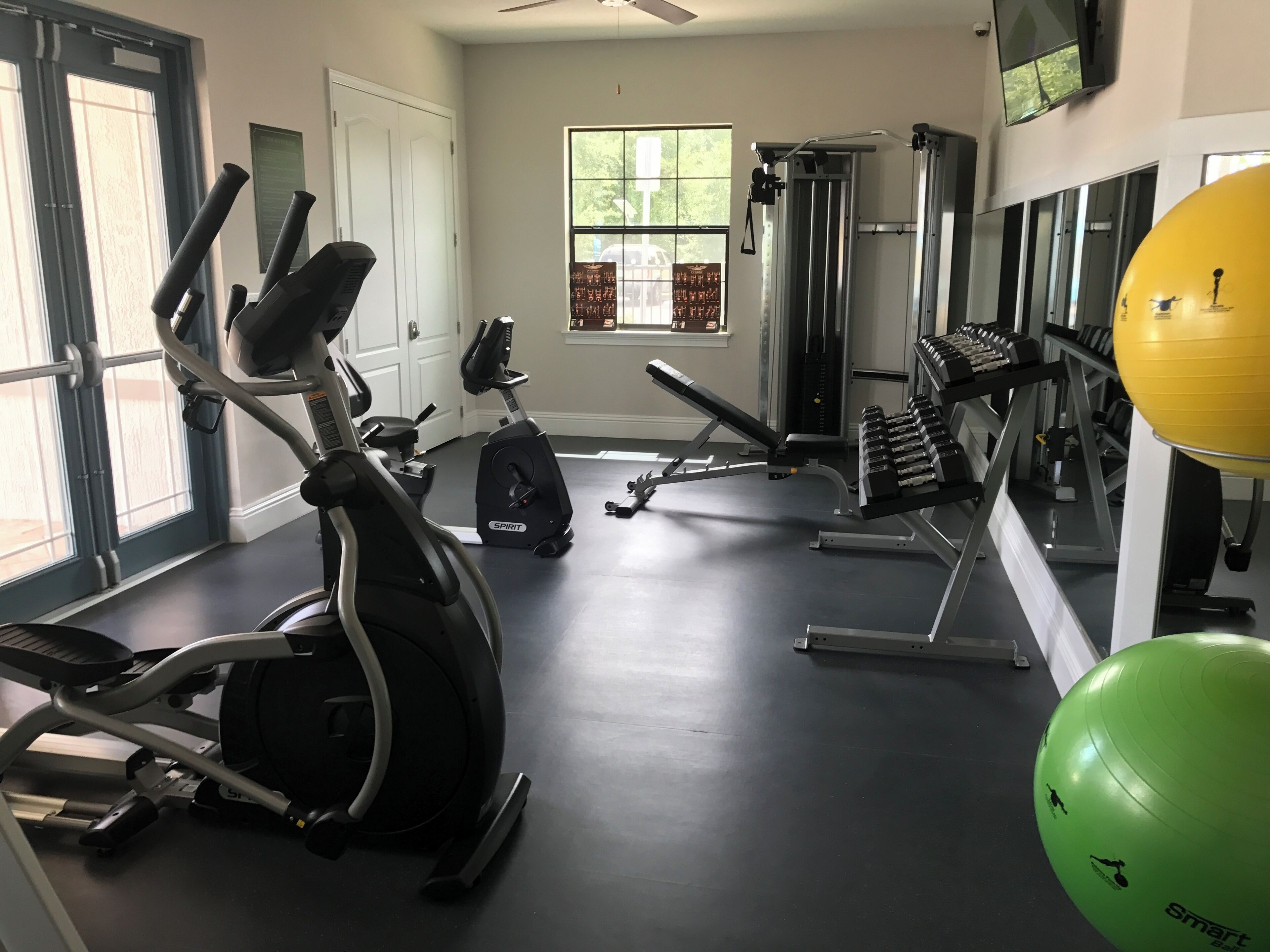 Une salle de sport équipée de machines de cardio, de matériel de musculation et de ballons d’exercice.
