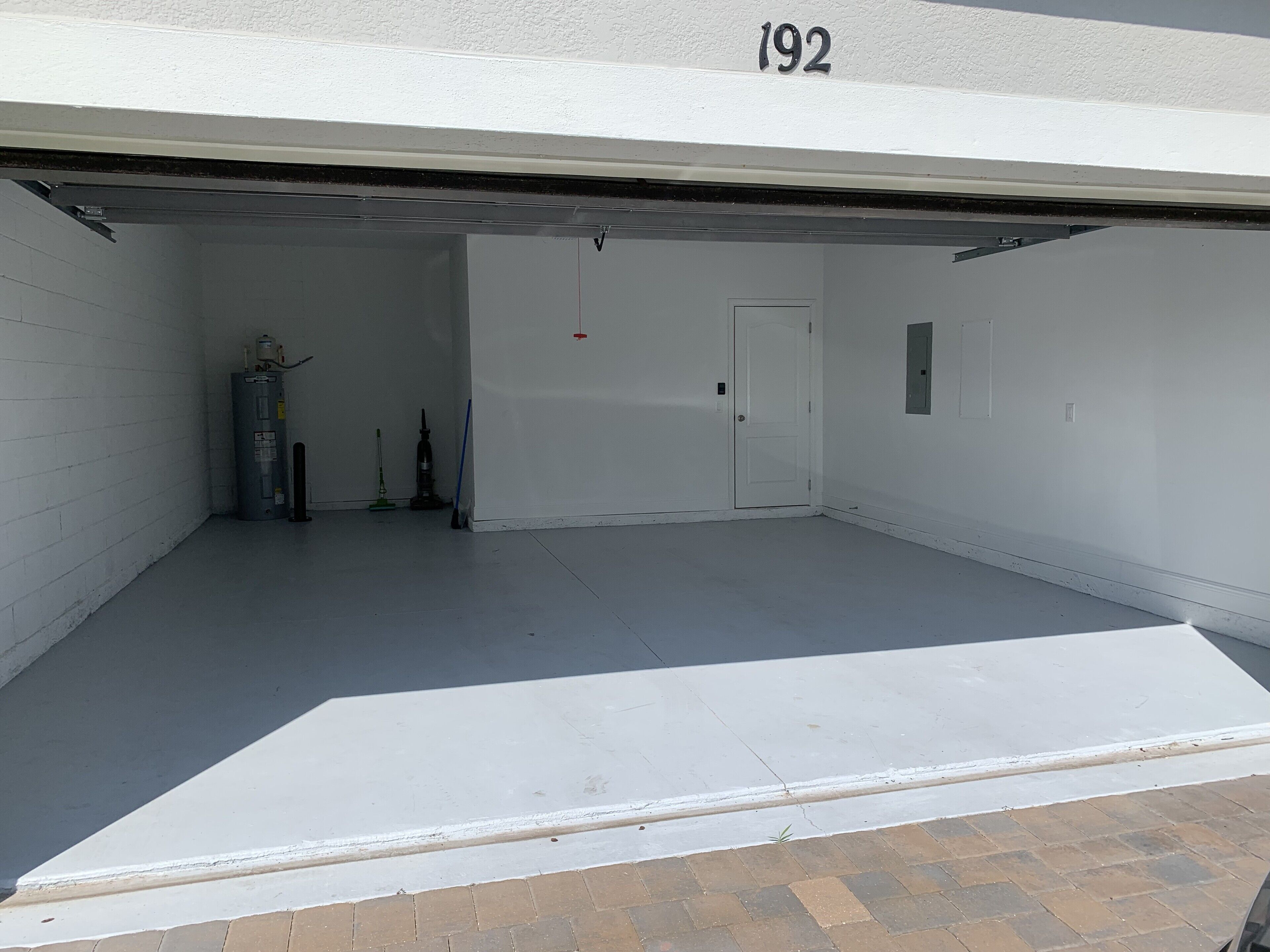 A clean, empty garage with a white door, a water heater, and a broom.