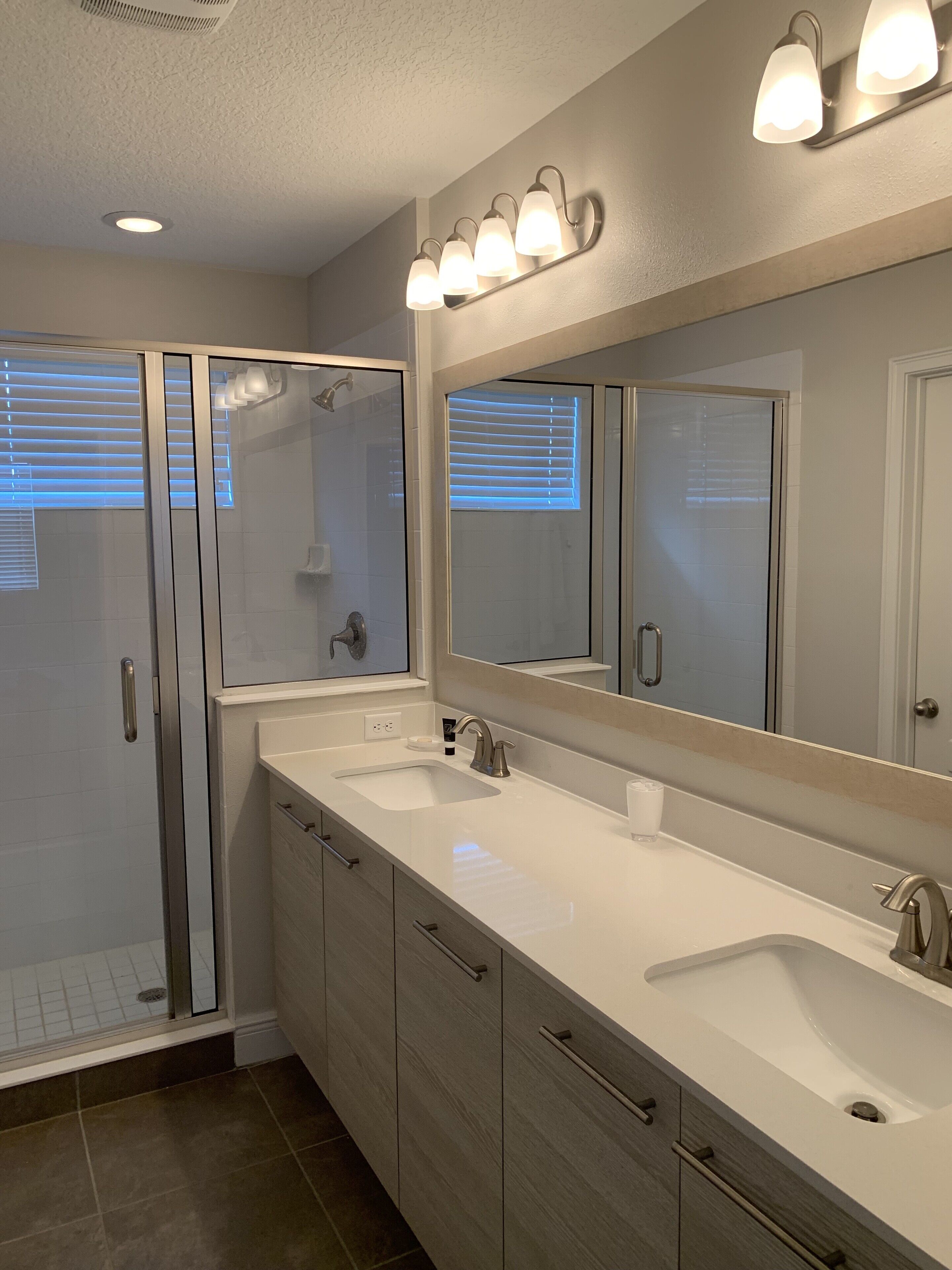 A bathroom with a double sink, a large mirror, and a glass shower enclosure.