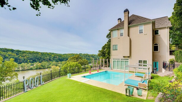 A two-story house with a swimming pool, a well-maintained lawn, and a view of a river. - Modern Retreat w/ River View in Roswell! (Roswell)