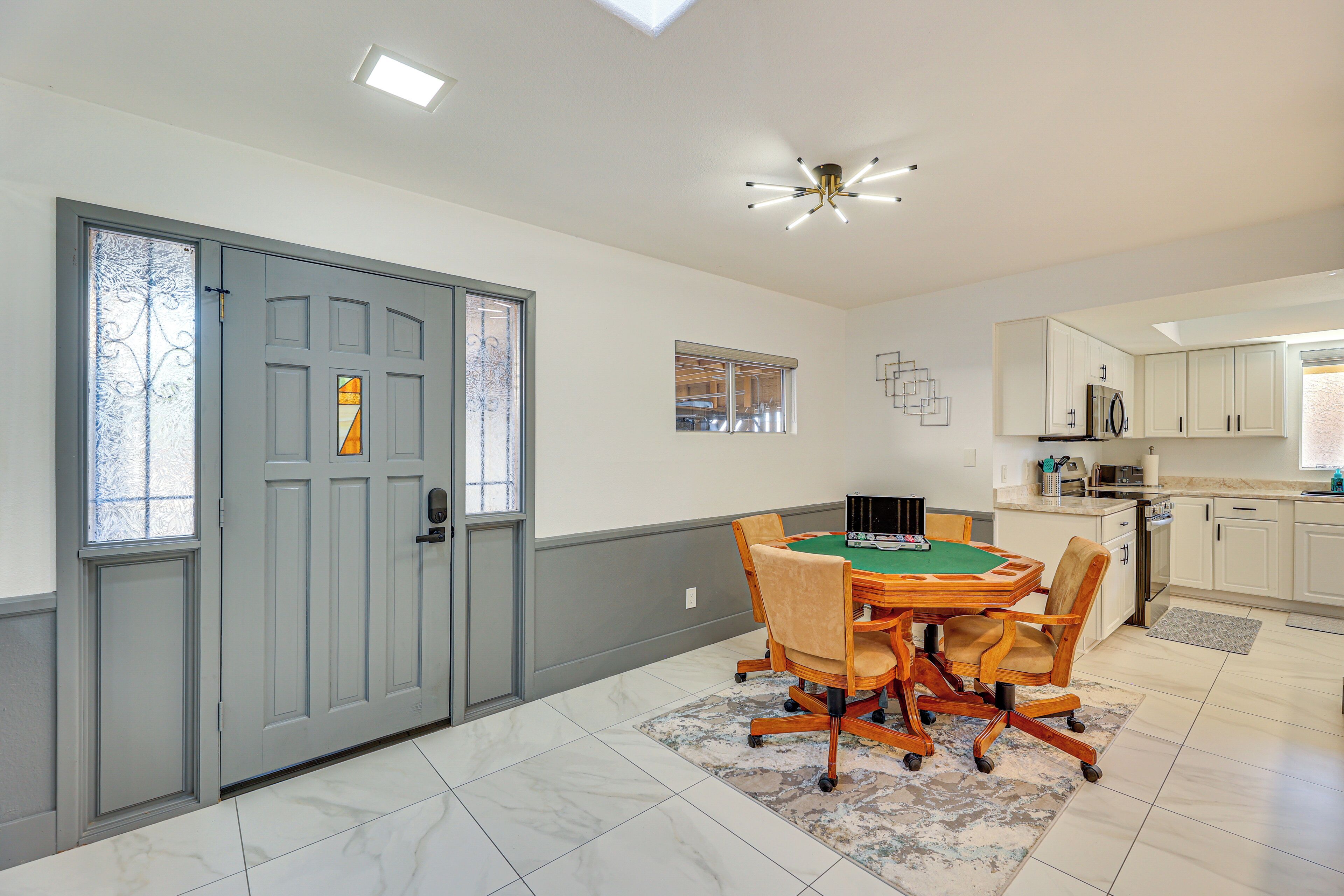 A dining area with a green felt table, wooden chairs, and a patterned rug.