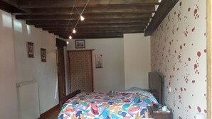 Une chambre à coucher avec un lit, un radiateur, un téléviseur et un mur orné d’un motif floral.