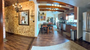 A modern kitchen with a central island, stainless steel appliances, and a rustic stone wall. - Merrily Yours! (Fortville)