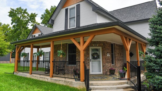 A two-story house with a covered porch, brick exterior, and a number 519 sign. - Merrily Yours! (Fortville)