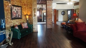 A spacious living room with a green sofa, a red sofa, and a dining area with a red lamp. - Merrily Yours! (Fortville)