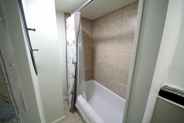 A bathroom with a shower, tiled walls, and a towel rack. - Studio- Behind Bert’s Market (Folly Beach)