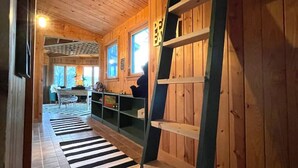 Een houten interieur met een betegelde vloer, een ladder en een uitzicht op het exterieur.