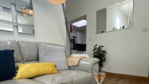Un salon moderne avec un canapé gris, une lampe sur pied, un miroir et une plante en pot.
