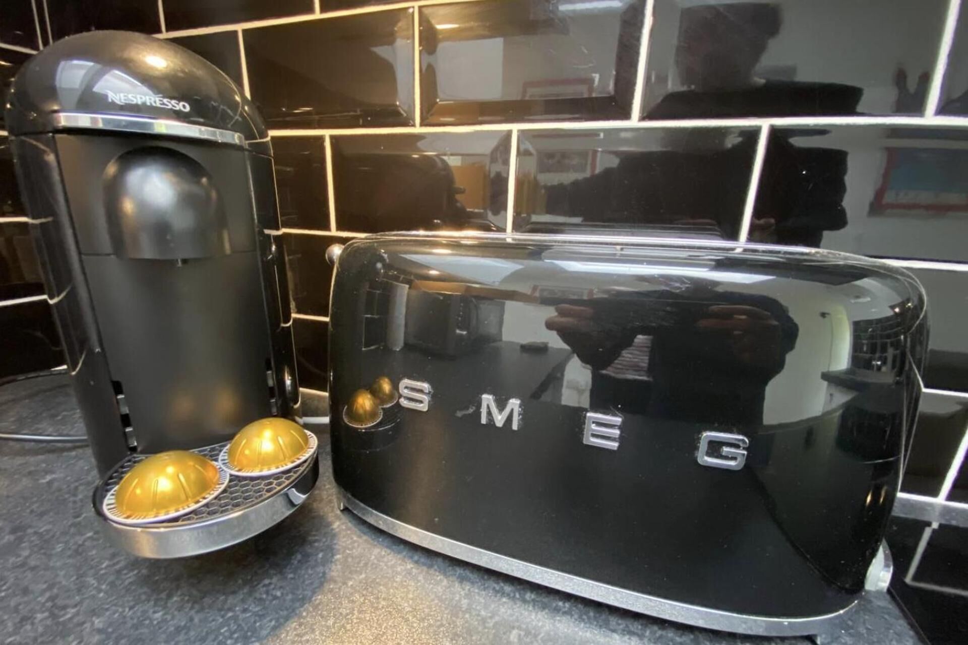 A Nespresso coffee machine and a black toaster with the brand name 'SMEG' on a kitchen counter.