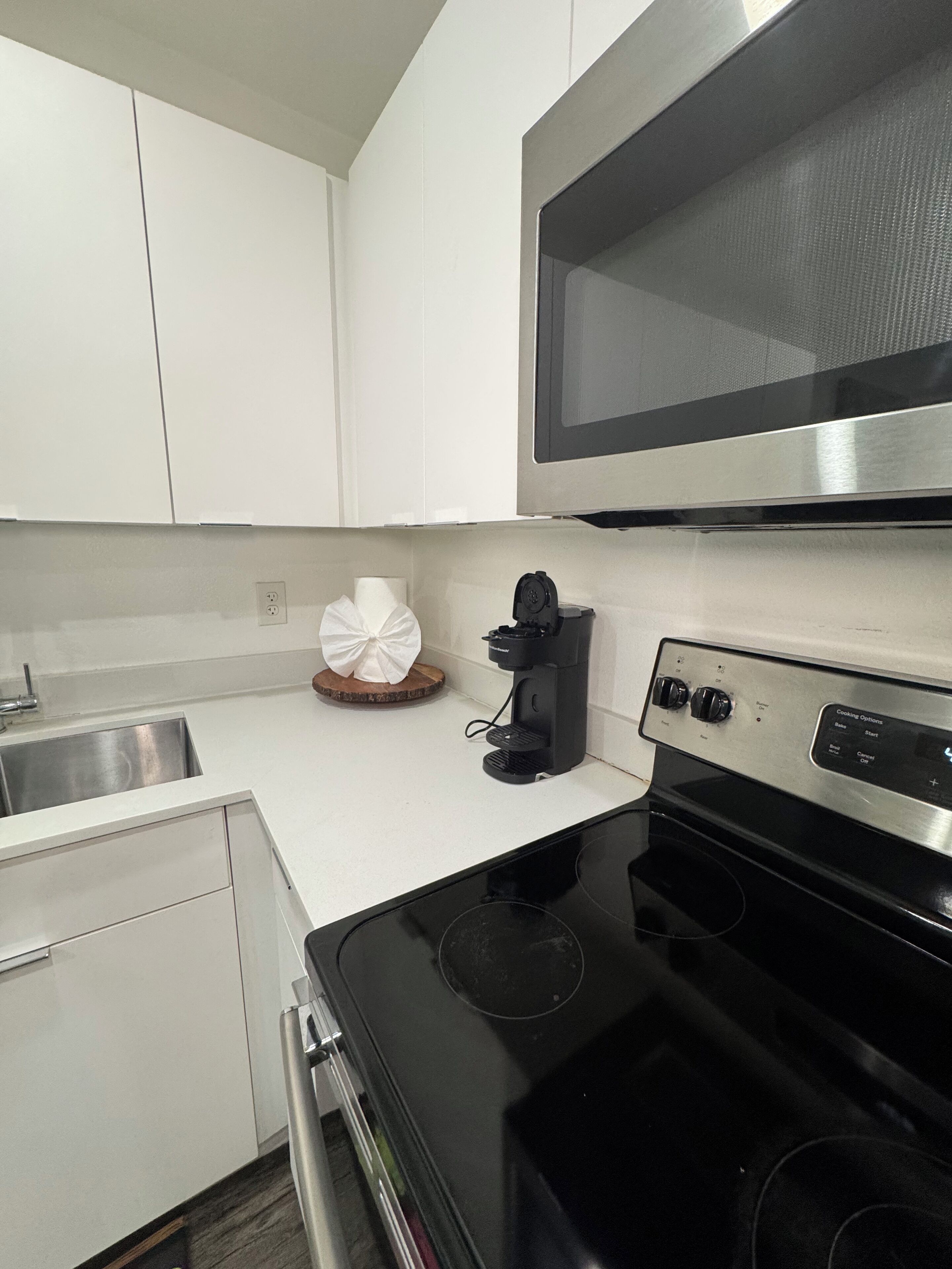 A kitchen with white cabinets, a black stove, a microwave, and a coffee maker.