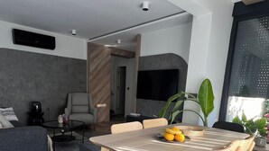 A modern living room with a dining area, featuring a wooden dining table with chairs, a sofa, and a coffee table.