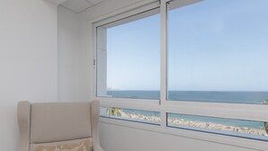 Een kamer met uitzicht op het strand door een groot raam.
