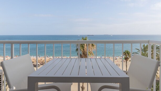 Een balkon met uitzicht op een strand en de zee.