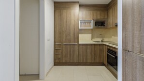 Een kleine keuken met houten kastjes, een magnetron, een spoelbak en een vaatwasser.