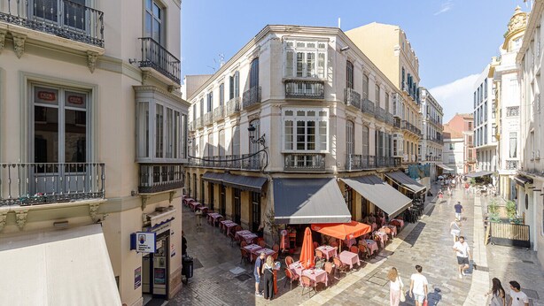 A street with outdoor seating and a café on the corner.